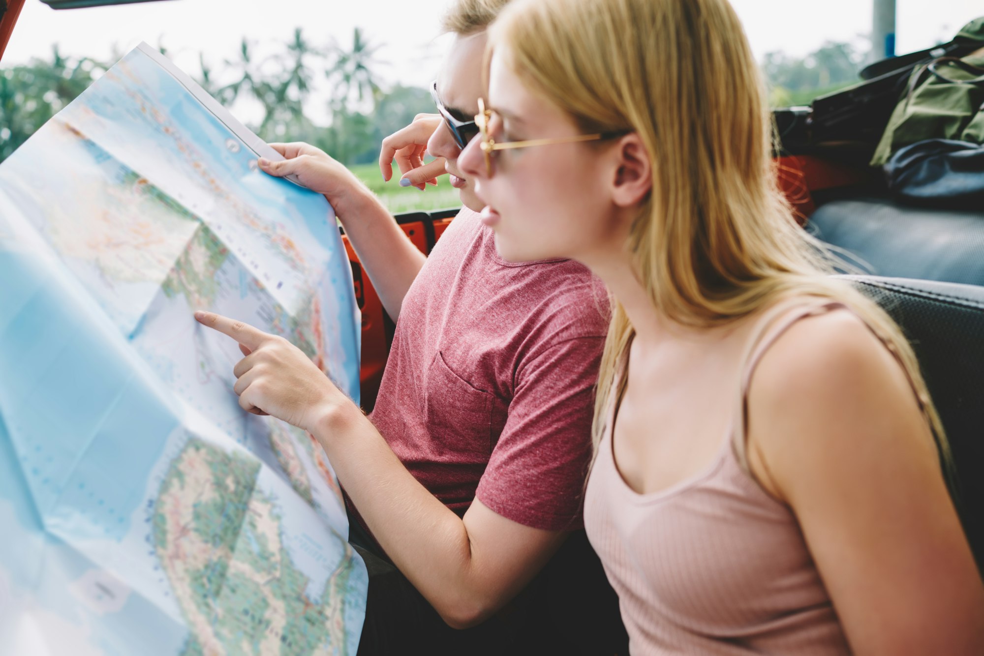 Traveling couple exploring map in car